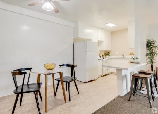 a dining area with a table and chairs and a kitchen with a refrigerator at University Park, California