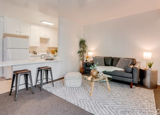 a living room with a couch and a kitchen with a bar and stools at University Park, Azusa, 91702