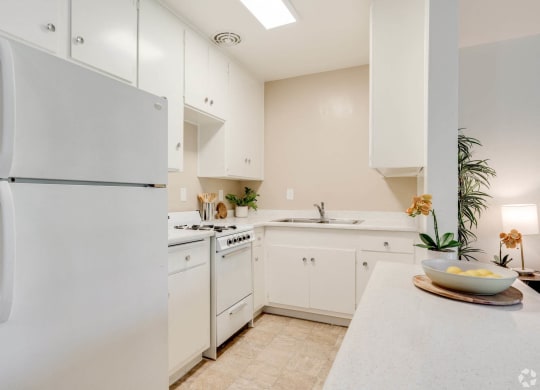 a white kitchen with white cabinets and a white refrigerator at University Park, Azusa, CA 91702
