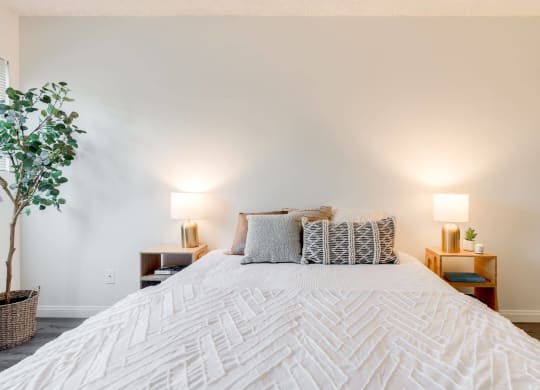 a bedroom with a large white bed and white walls at University Park, Azusa
