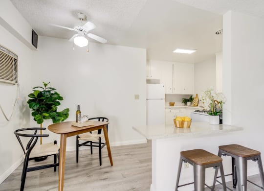 a living room with a kitchen with a bar and stools and a ceiling fan at University Park, California, 91702