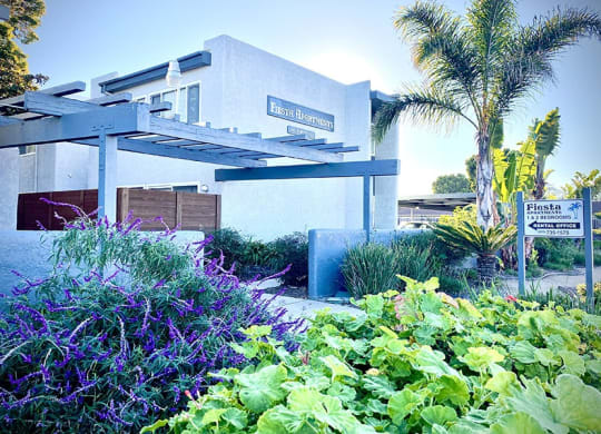 a white building with a blue awning and a palm tree in the background at Fiesta Apts, Lompoc, 93436