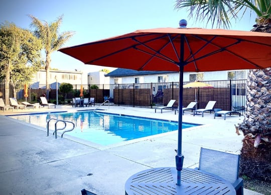 a pool with a table and umbrella next to it at Fiesta Apts, Lompoc, CA