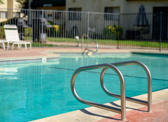 a swimming pool with a ladder in front of a building at Park Columbia Apts, Hemet, 92544