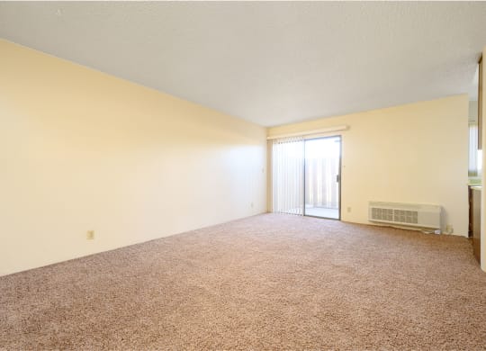 an empty living room with a door leading to a balcony at Park Columbia Apts, Hemet California