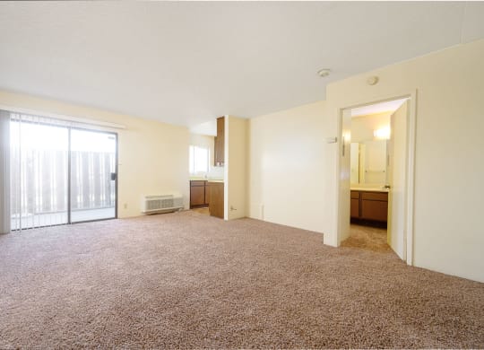 a bedroom with a large window and a door leading to a kitchen at Park Columbia Apts, Hemet, 92544
