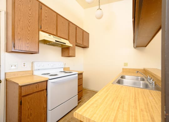 a kitchen with wooden cabinets and white appliances at Park Columbia Apts, Hemet, CA