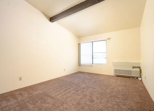 a bedroom with carpeted floors and a large window at Park Columbia Apts, California, 92544