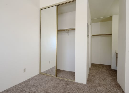 a bedroom with white walls and a carpeted floor at Park Columbia Apts, California