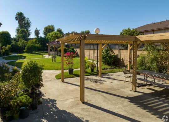 a patio with a pergola in a garden at Flamingo Garden Senior Apts, El Monte, CA