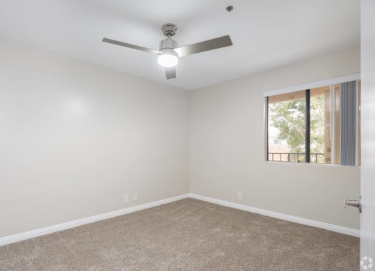 an empty room with a ceiling fan and a window at Huntington Terrace North Senior, Huntington Beach, CA 92648