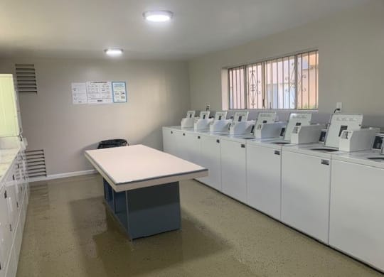 an empty room with washing machines and a table at North View Terrace, Montebello California