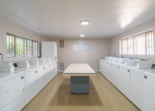 an empty kitchen with white cabinets and a table at North View Terrace, Montebello, CA