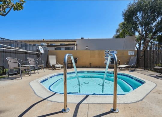 our resort style hot tub is next to our patio with chairs and a fence at Huntington Terrace North Senior, Huntington Beach California