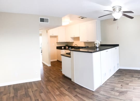 an empty kitchen with white cabinets and a ceiling fan at Terramonte Apartment Homes, Pomona, California