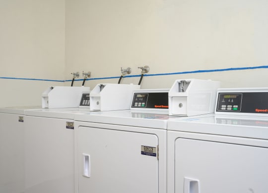 a row of washers and dryers in a laundry room at Villa Hemet, Hemet, CA