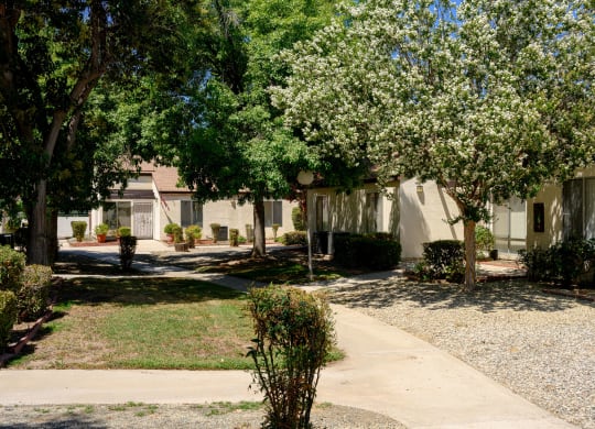 a building with a sidewalk and trees in front of it at Villa Hemet, Hemet, CA