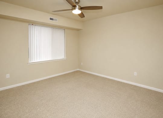 A room with a ceiling fan and a window with blinds.