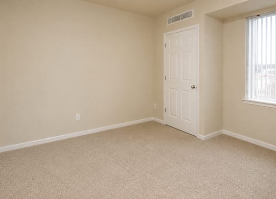 A room with a carpeted floor and a door.
