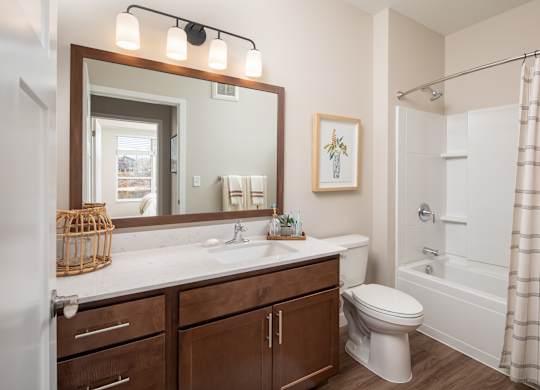 A bathroom with a white toilet, a sink with a mirror above it, and a shower with a curtain.