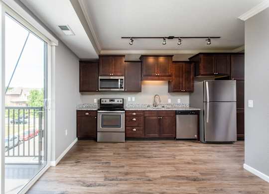 a kitchen with dark wood cabinets and stainless steel appliances  at Victoria Park and V2 Apartments, Minnesota