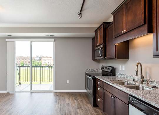 a kitchen with wood floors and a sliding glass door leading to a balcony  at Victoria Park and V2 Apartments, St. Paul