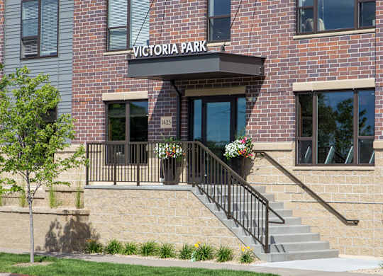 the entrance of a brick building with a sign that says victoria park  at Victoria Park and V2 Apartments, Minnesota, 55102