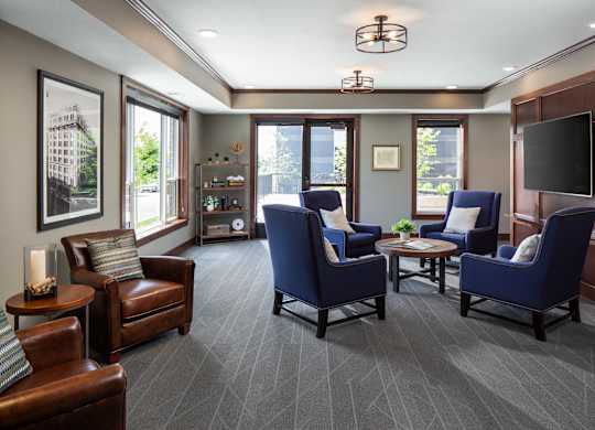 a community room filled with furniture and a large window  at Victoria Park and V2 Apartments, St. Paul, 55102