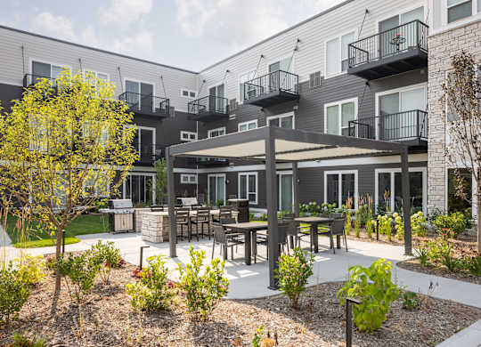 A patio area with a table and chairs surrounded by plants and trees.