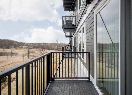 A balcony with a black railing and a glass door.