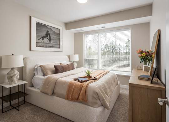 A bedroom with a bed, nightstand, and a painting on the wall.