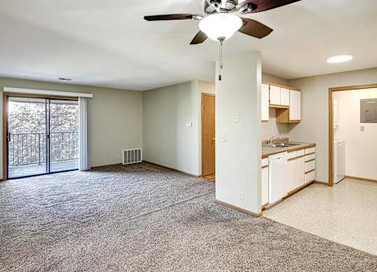 A spacious living room with a ceiling fan and sliding glass doors leading to a backyard.