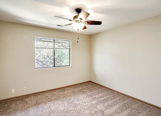 A room with a ceiling fan and a window.