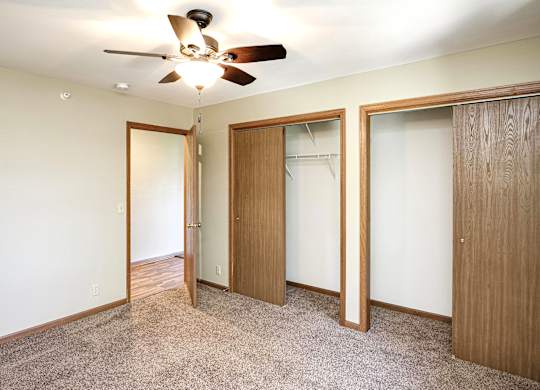 A room with a ceiling fan and three doors.