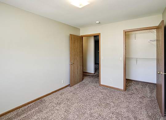 A room with a carpeted floor and two doors.