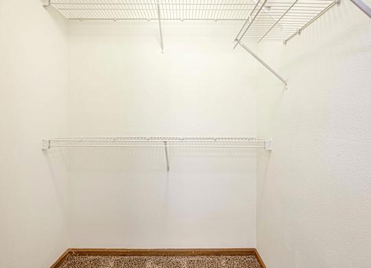 A white wall with a metal rack on top and a brown carpet on the floor.