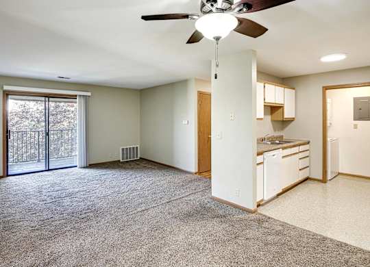 A spacious living room with a ceiling fan and sliding glass doors leading to a backyard.
