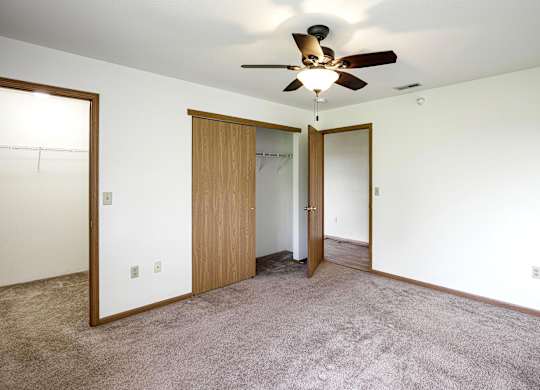 A room with a ceiling fan and carpeted floor.