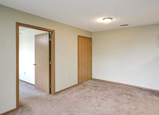 A room with a carpeted floor and two wooden doors.