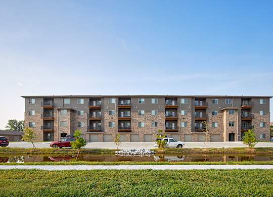 A modern apartment building with a parking lot in front.