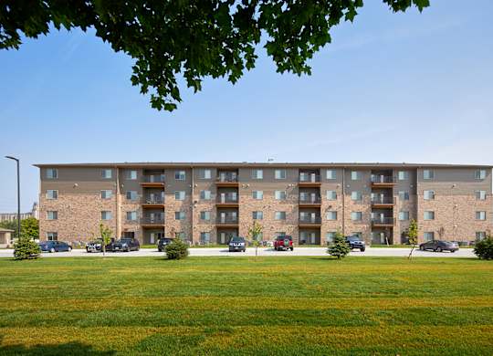 A large apartment building with a grassy area in front.