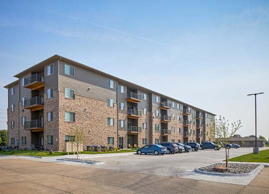 A large apartment complex with a parking lot in front.