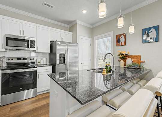 A modern kitchen with a granite countertop and stainless steel appliances.