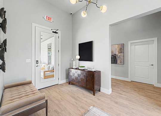 A living room with a brown leather chair, a wooden cabinet, a flat screen TV, and a white door.
