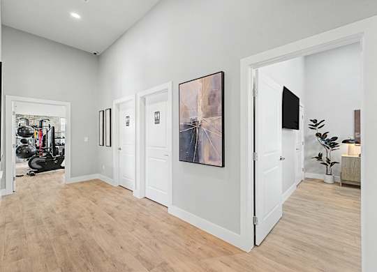 A long hallway with a gym in the background and a painting on the wall.