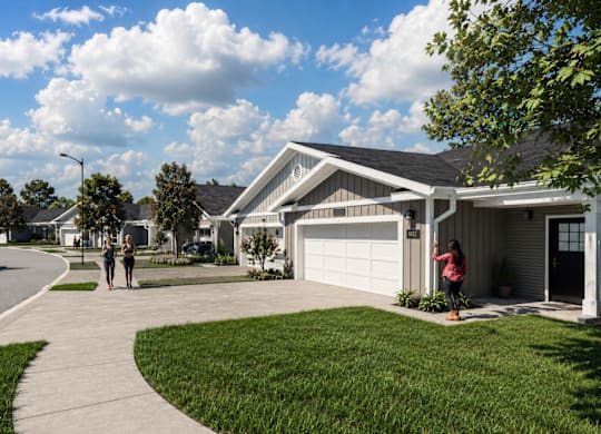 Two people are walking on a sidewalk in front of a house.