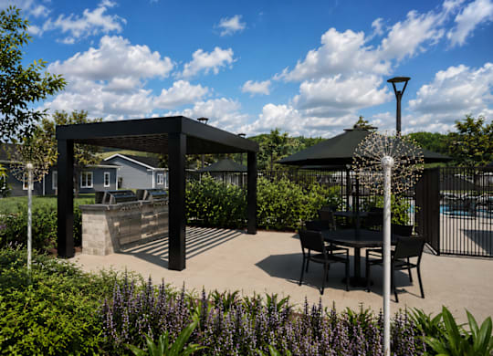 A black metal structure is in the middle of a garden with a table and chairs.