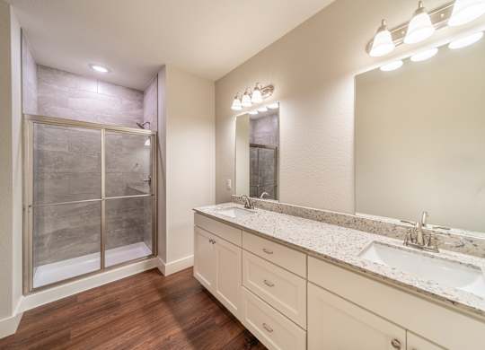 A bathroom with a sink, mirror, and a shower with a glass door.