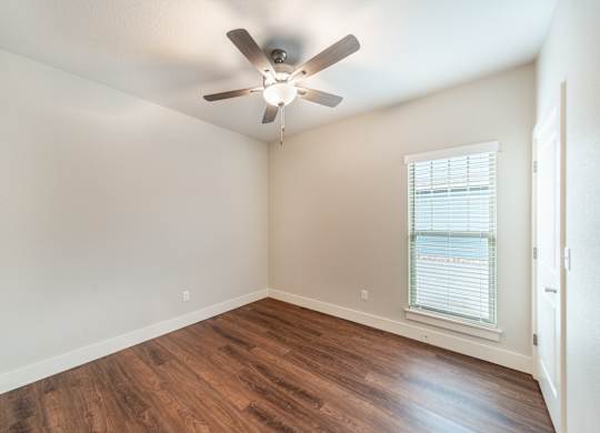 A room with a ceiling fan and a window with blinds.