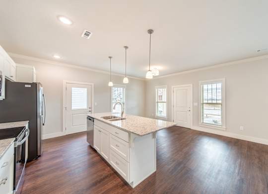 A kitchen with a refrigerator, sink, and cabinets.